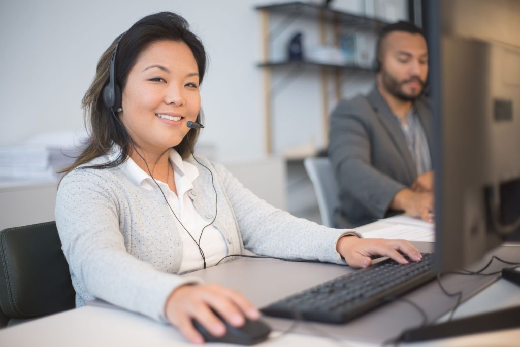 Two call center employees working with headsets in a modern office setting.